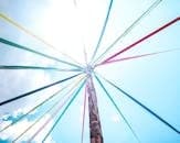 Colorful ribbons adorn a maypole on a sunny day, symbolizing spring festivities. Beltane
