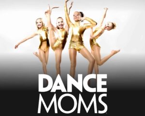 Dance Moms promotional image from disney plus with four of the shows dancers in gold outfits