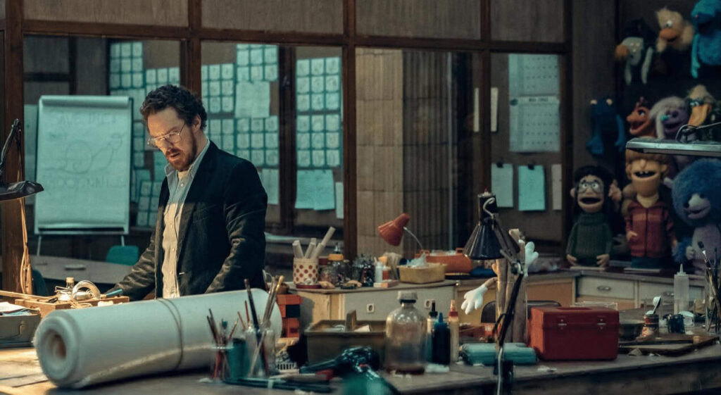 Benedict Cumberbatch with a large blue puppet in a scene from Eric, a psychological drama Netflix show.