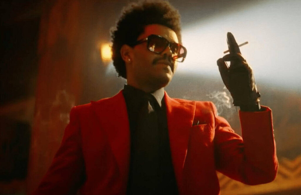 The Weeknd in his iconic red suit and sunglasses, a top streaming artist on Apple Music.