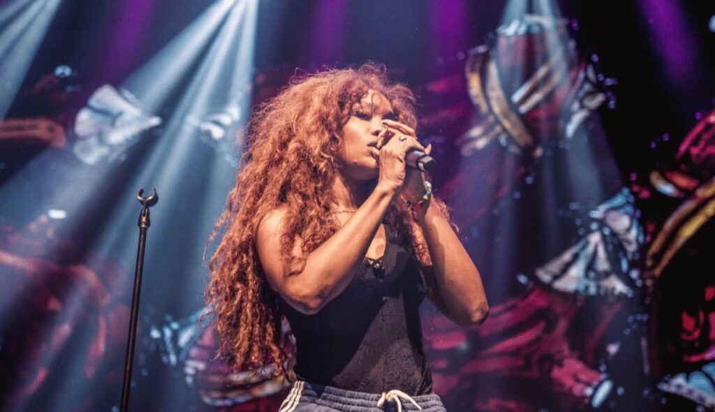 SZA performing live on stage with a microphone, a top streaming artist on Apple Music.