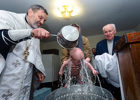 A baby being baptized in a church by a priest during a religious ceremony.