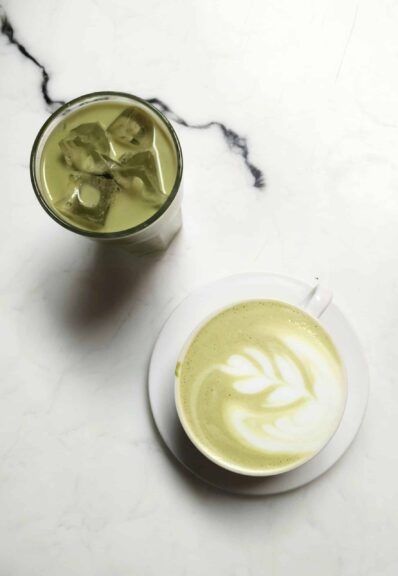 Elegant matcha latte with latte art and iced green tea on a marble table, perfect for tea enthusiasts.