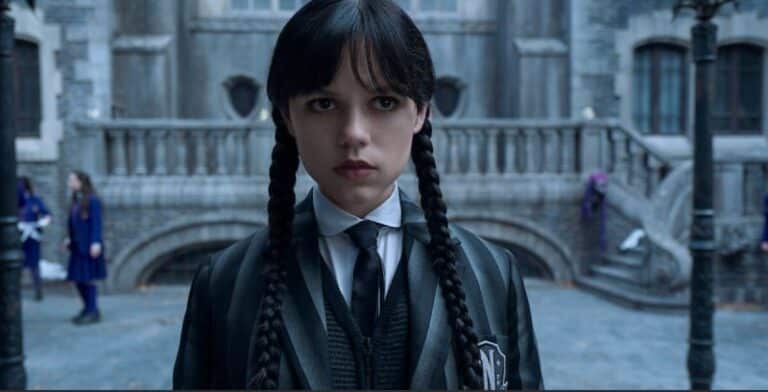 Jenna Ortega as Wednesday Addams, with braided pigtails and a serious expression, wearing her school uniform. Season 3