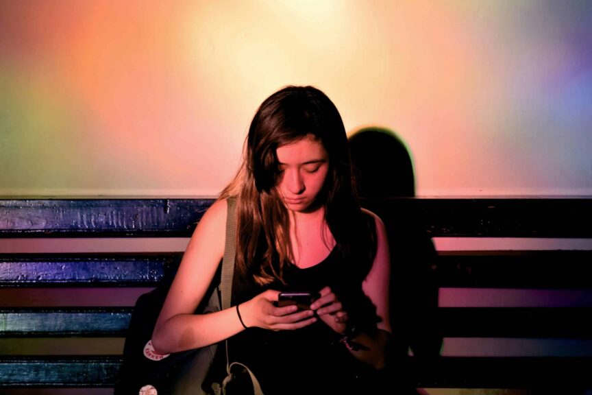 woman wearing black tank dress, using smartphone. Mindful news consumption