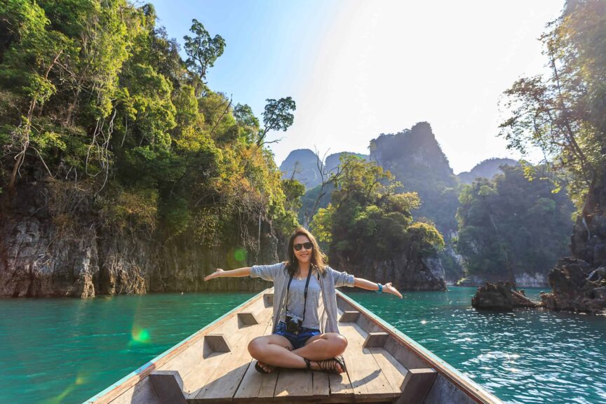 Asian woman relishing a serene boat journey through the lush karst landscape of Thailand's Khlong Sok. Ethical Tourism