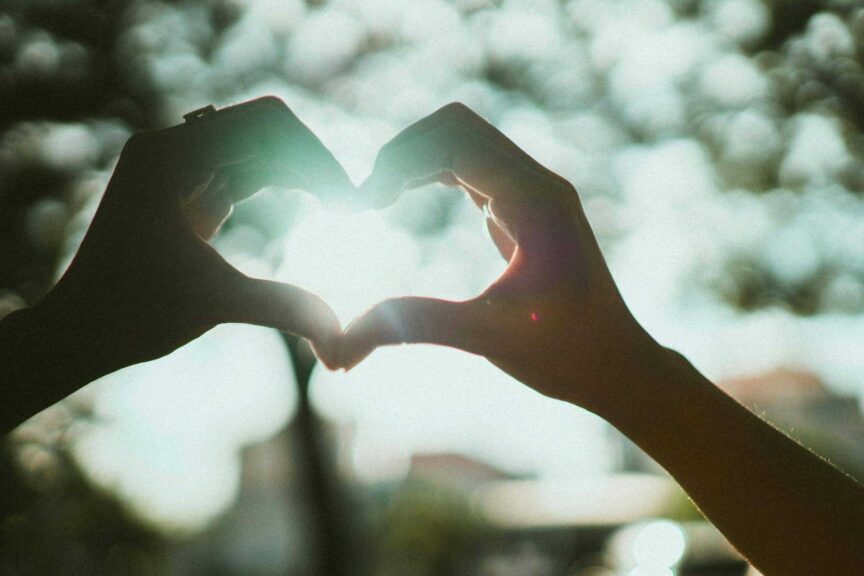 Close-up of hands creating a heart shape under bright sunlight, symbolizing love and connection. Venus in Gemini