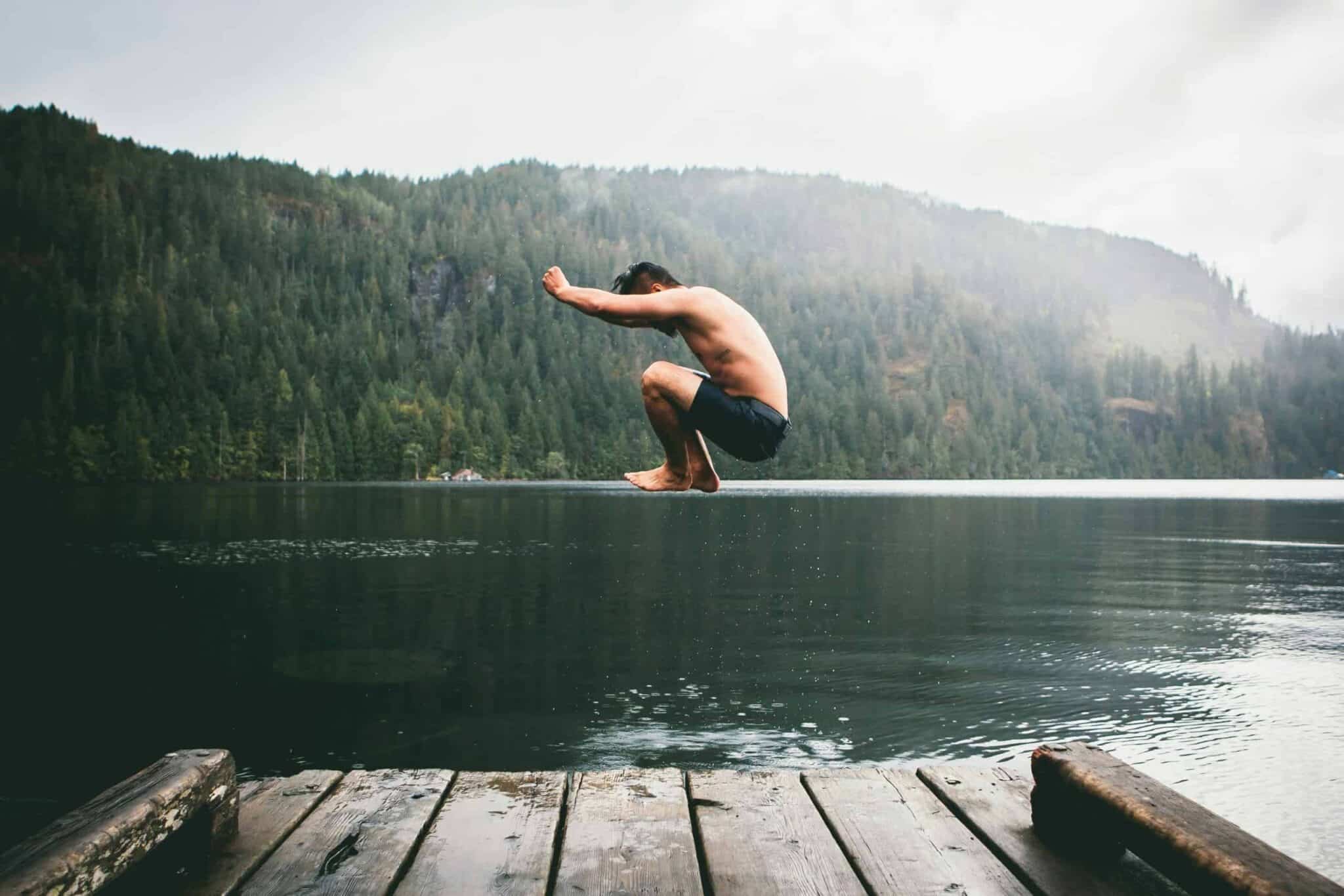 Man jumping into water from a dock