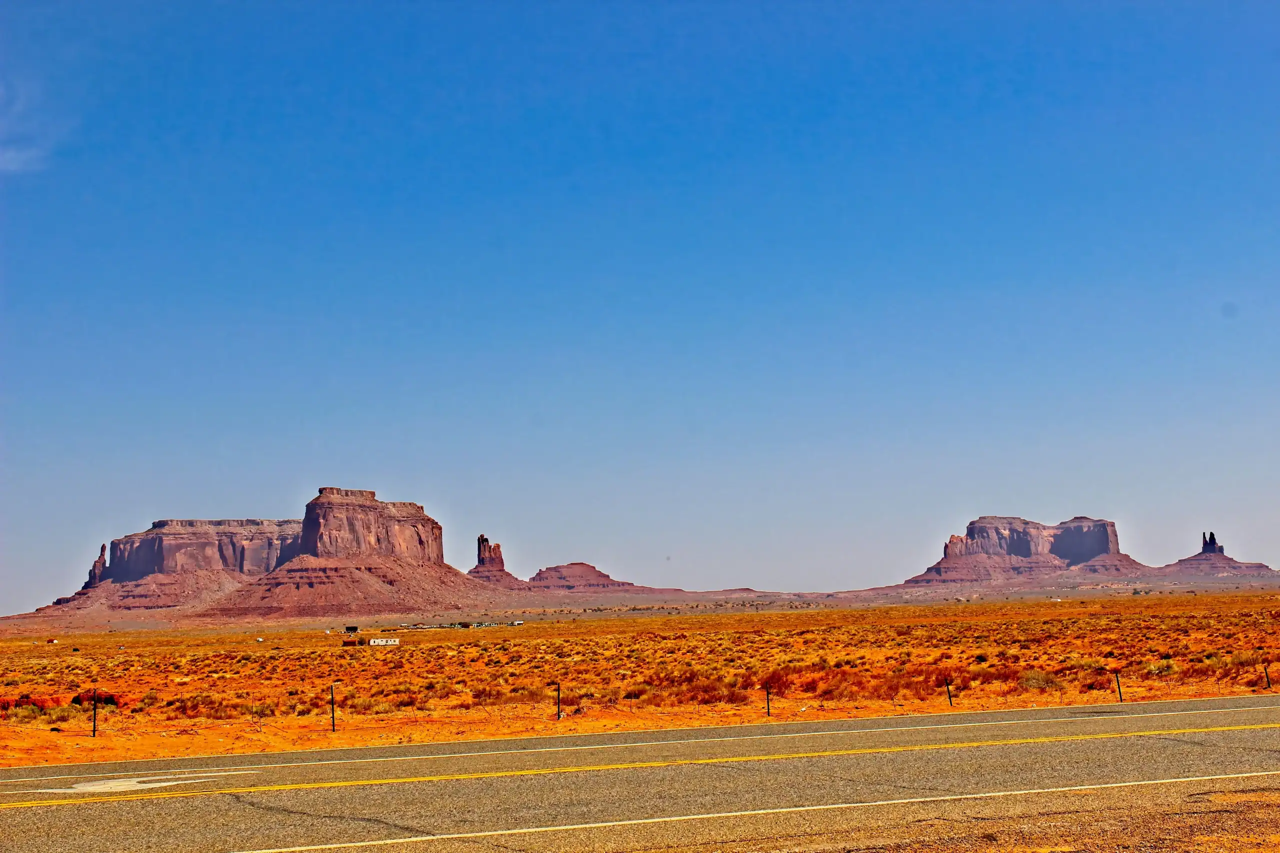 Rock formations against a desert landscape along a highway in Monument Valley, Utah.