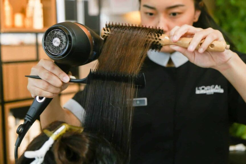 Hairdresser expertly styles hair using a brush and dryer in a salon setting. haircare tools