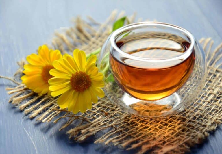 Glass cup of herbal tea with yellow flowers on a textured background. , coffee alternatives