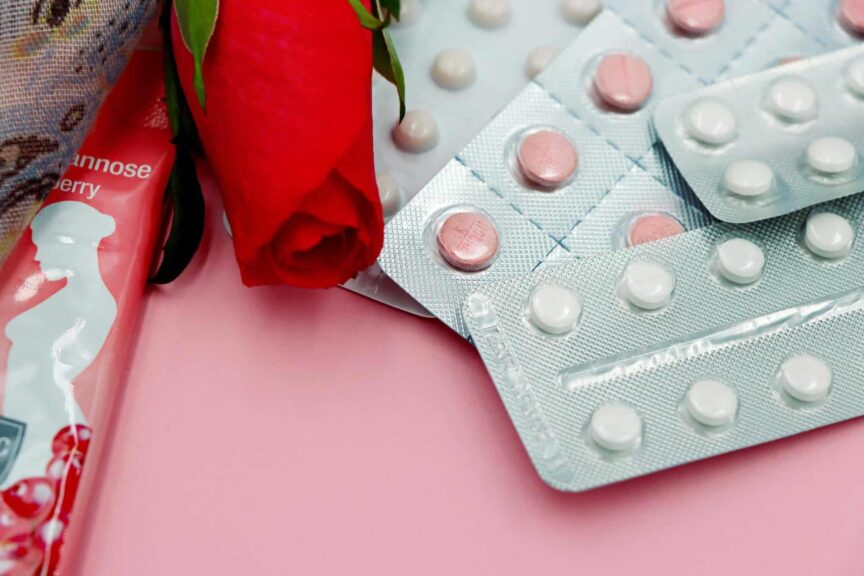 Pills and red rose on pink background, symbolizing healthcare and romance. hormonal birth control