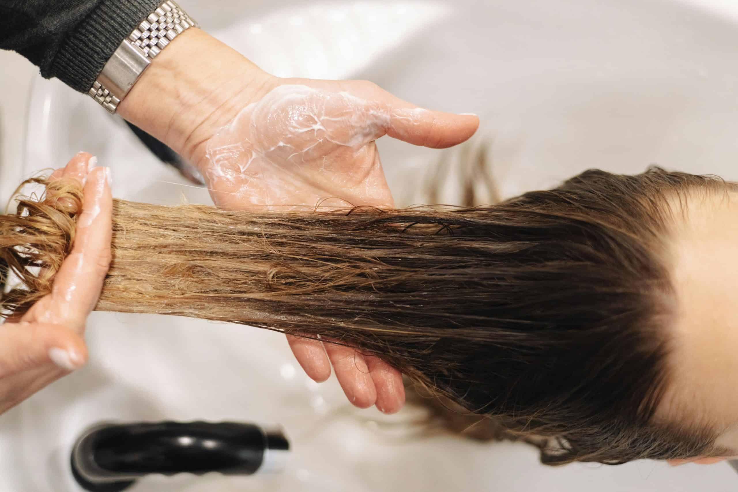 Close-up of a professional hair wash in a salon setting, highlighting hand technique.