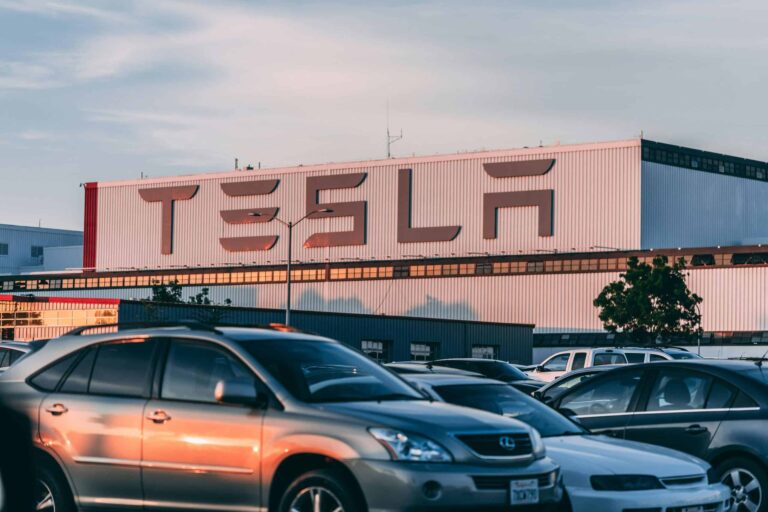 Tesla factory with parked cars during sunset, showcasing modern automotive industry vibes. Tesla Model 3