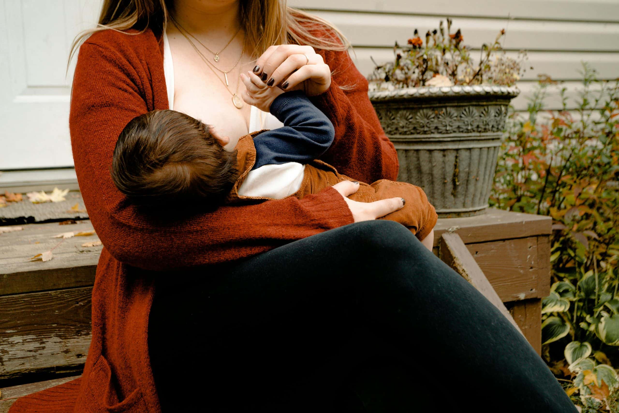 Intimate moment of a mother breastfeeding her child on a porch, symbolizing warmth and care. National Breastfeeding Week
