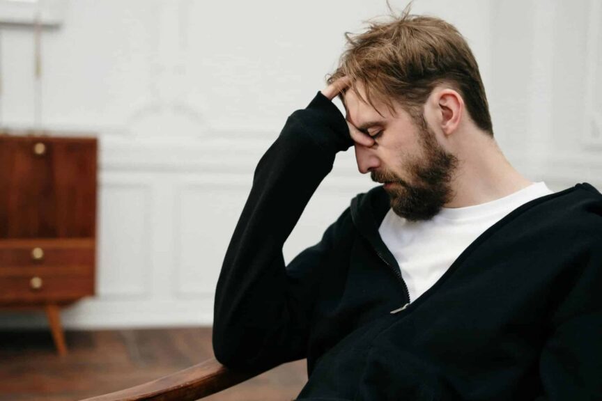 A man sits pensively with his hand on his face, capturing a moment of introspection and stress, sabotaging, relationship