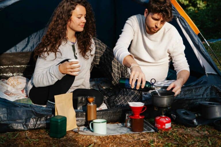 A couple brewing coffee with a chemex in a campsite, enjoying a relaxing outdoor experience. campsite safety