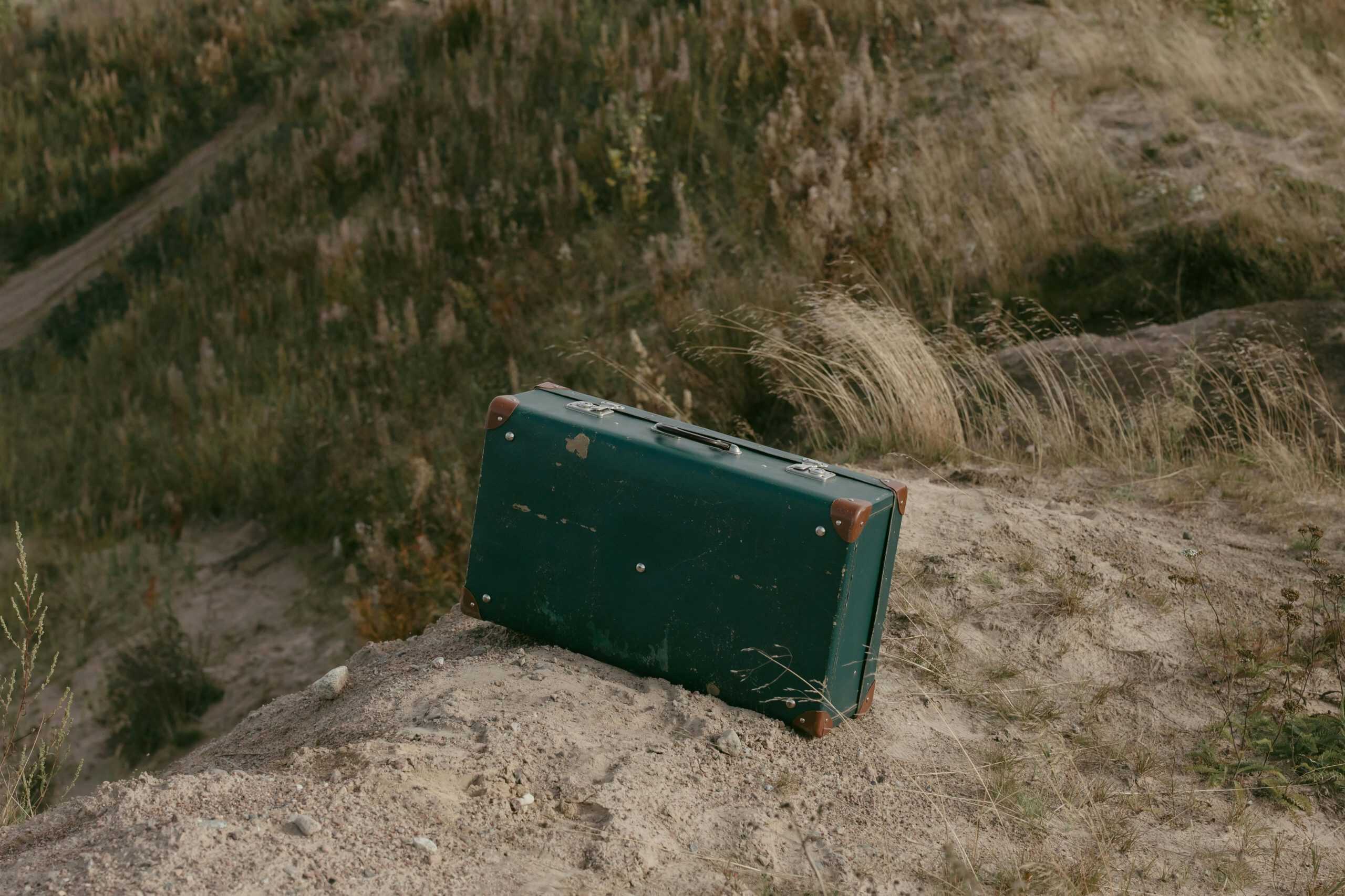 An old suitcase resting on a natural grassy hilltop, symbolizing adventure.