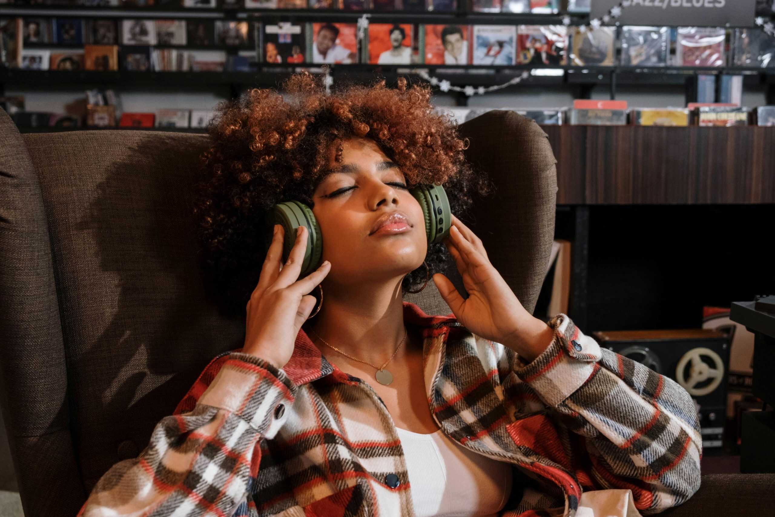 Cozy scene of a woman with curly hair enjoying music in a record store.