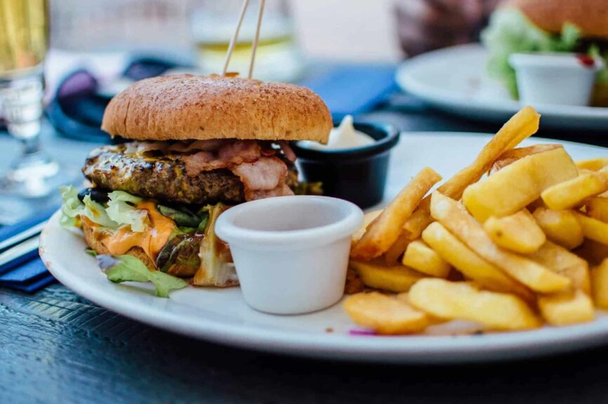 Close-up of a juicy burger and crispy fries served with sauces, perfect for a hearty meal. fast food