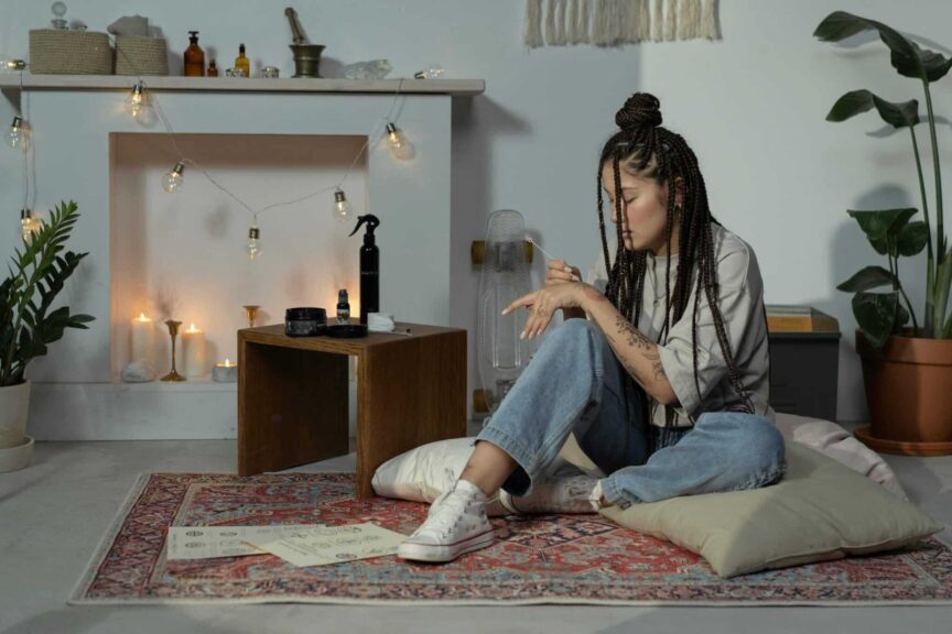 Woman with Afro braids in a cozy boho room. Featuring candles, plants, and cushions. boho braids