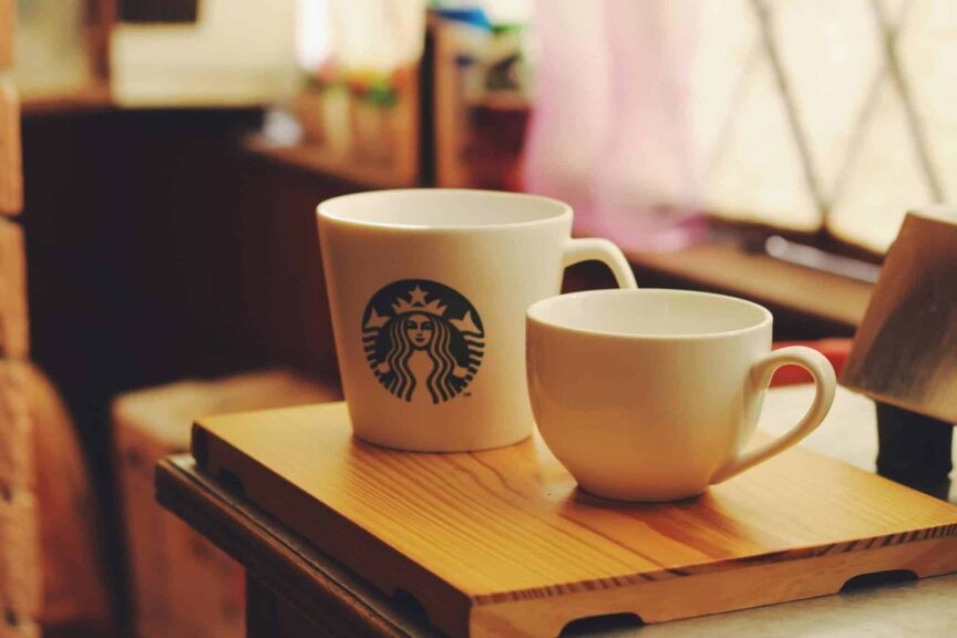 This photograph has two coffee mugs. One features a Starbucks logo.