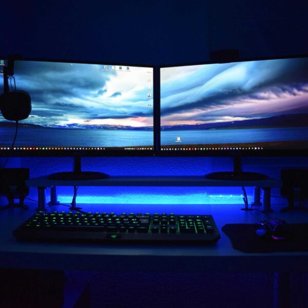 Dual monitors with blue lighting on a gaming desk setup. accessories