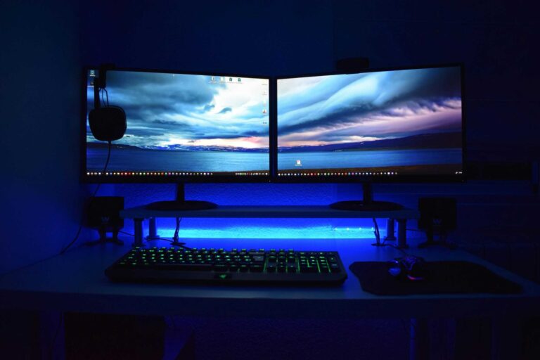 Dual monitors with blue lighting on a gaming desk setup. accessories