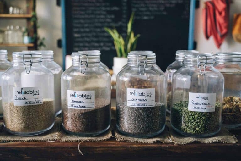 Glass jars in a store containing organic seeds like quinoa and flax, promoting sustainable living. chia seeds flax seeds