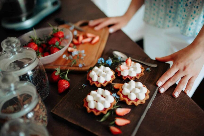 Freshly prepared strawberry tarts with cream on a wooden board, perfect for a delightful dessert., Labor Day