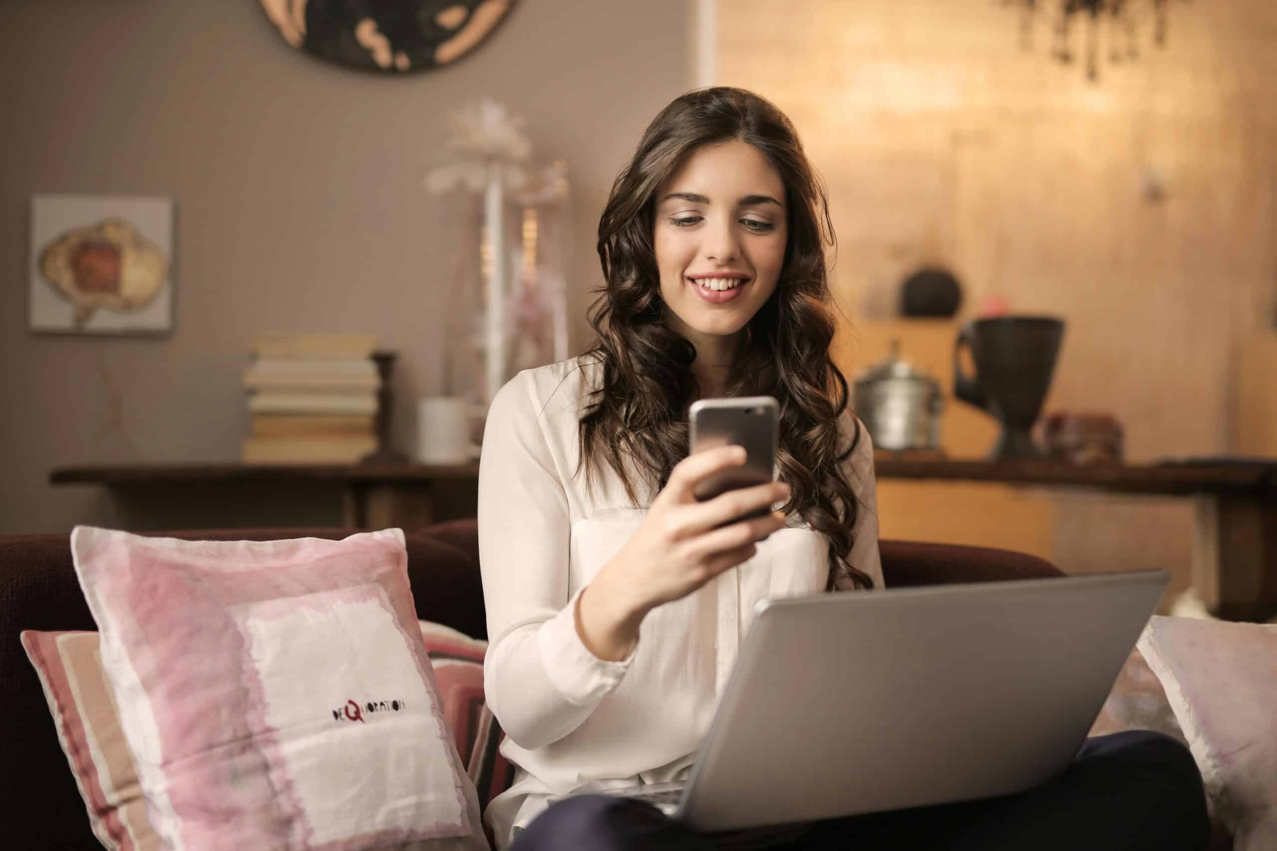 A woman enjoying leisure time using her smartphone and laptop in a cozy living room. Faith, social media