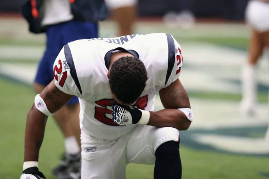 NFL Preseason, Football player in uniform kneeling before a game, displaying focus and determination.