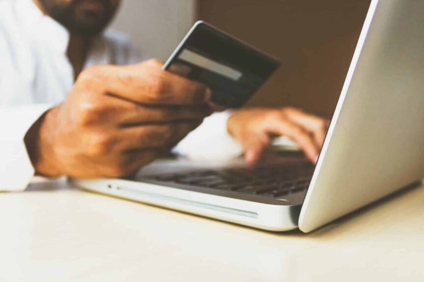 A person using a laptop and holding a credit card. , travel scams
