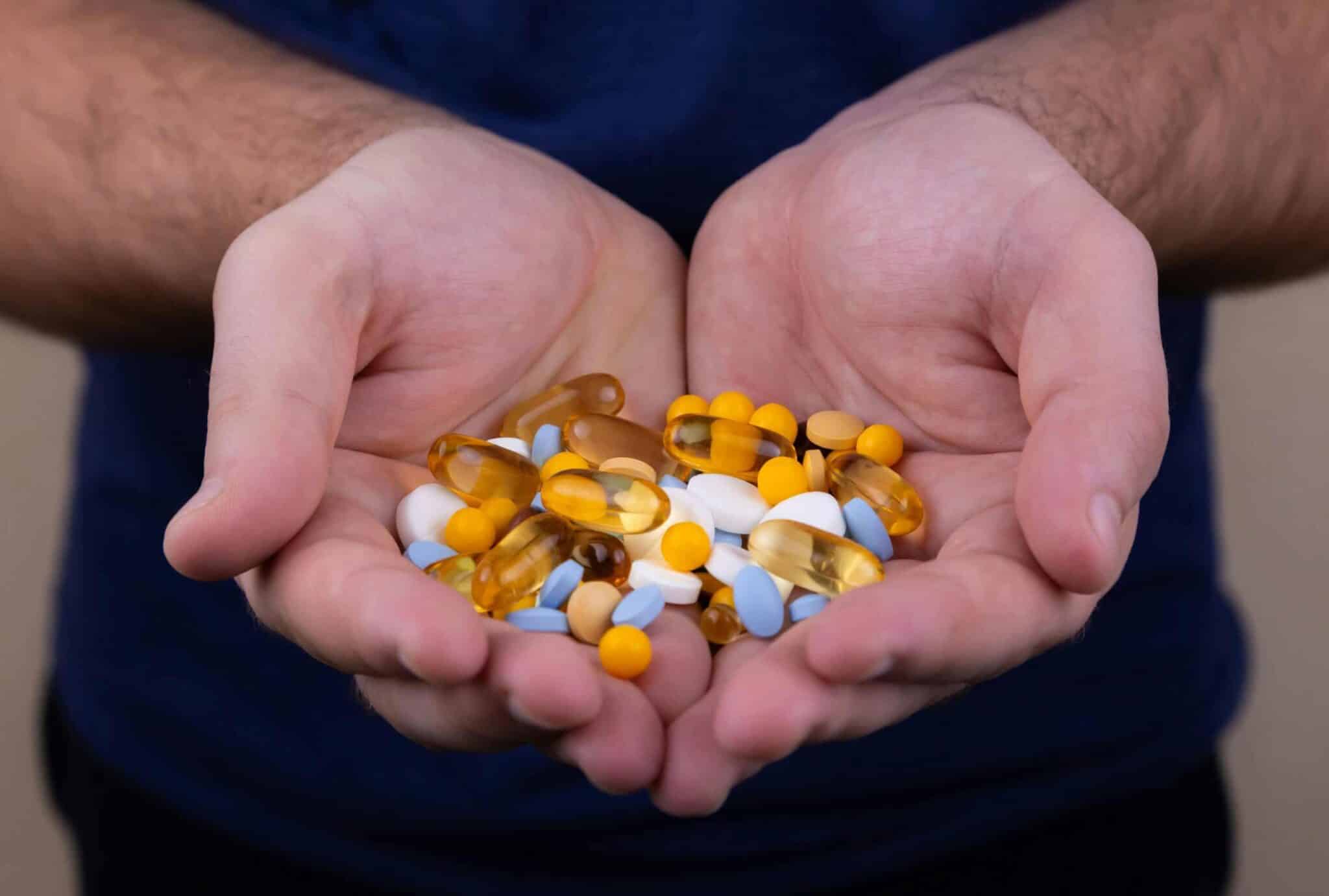 A person holding a handful of pills / vitamin patch