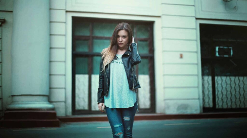 This photo features a woman in a city scene. The blue jeans she wears are part of her street style ensemble.