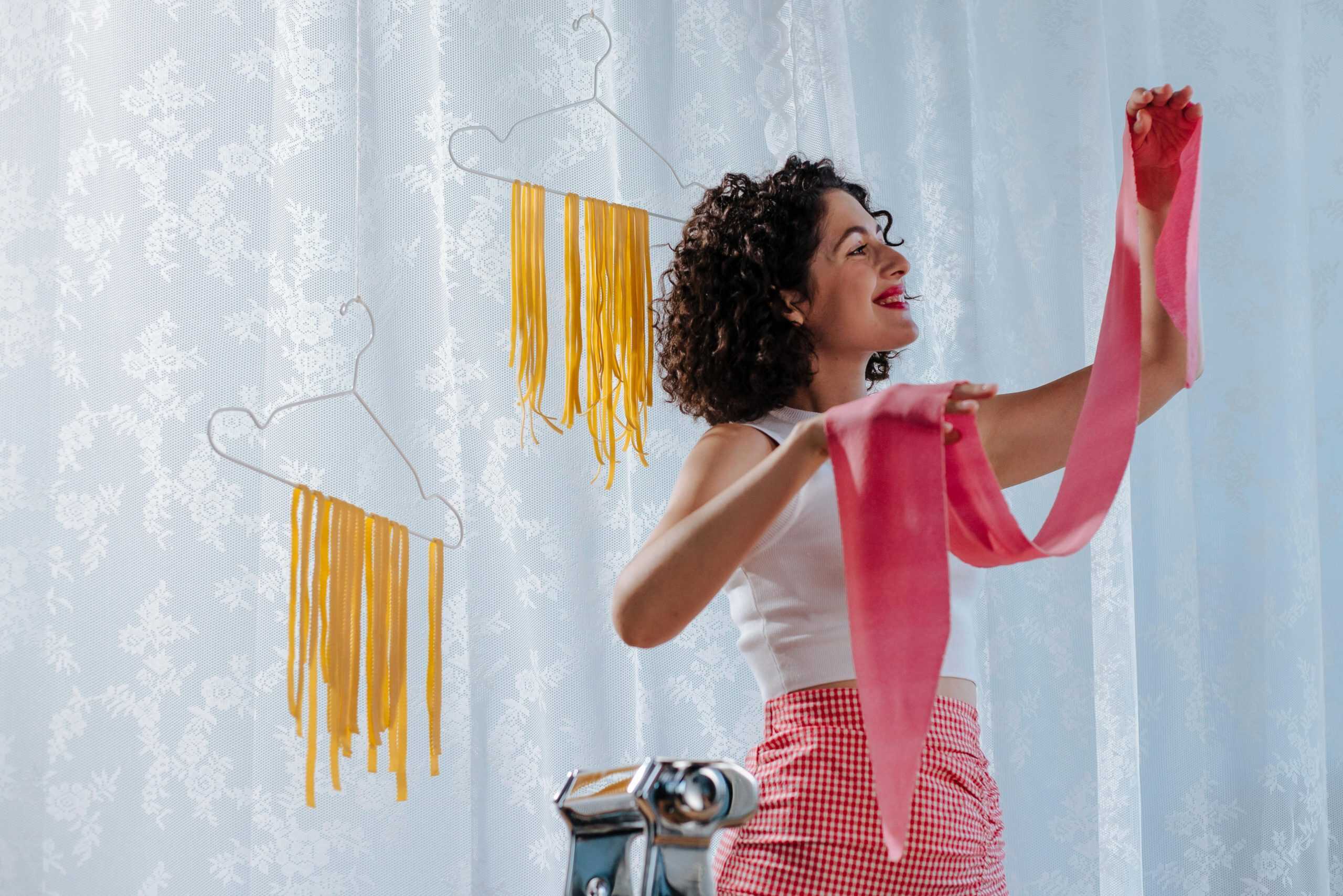 Smiling woman making homemade pasta, enjoying the creative culinary process indoors.