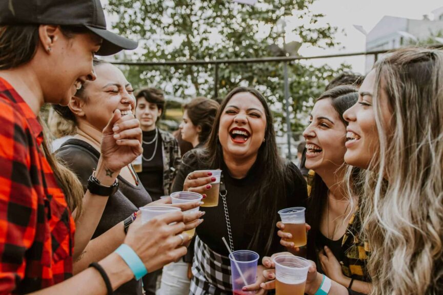 breweries, seasonal beer, Group of young women laughing and enjoying drinks outdoors in São Paulo.