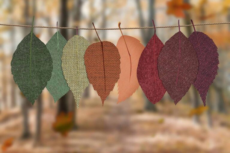 Fabric leaves hang on a rope, showcasing autumn colors in a forest backdrop. sustainable fall decor