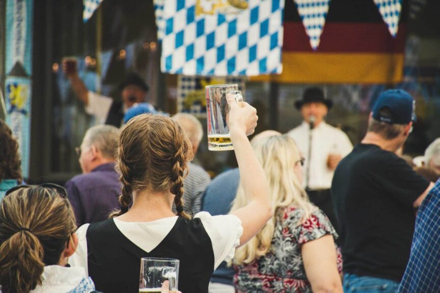 A lively crowd enjoys Oktoberfest outdoors with beer mugs raised. Perfect for festival season visuals.