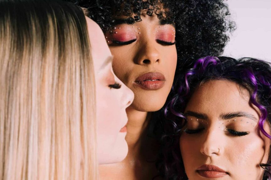 long eyelashes, casual relationships, three women with artistic makeup and closed eyes, showcasing fashion beauty.