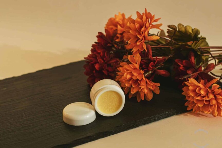 Close-up of orange flowers and cosmetic cream on slate, evoking fall aesthetics. September 2025 beauty launches