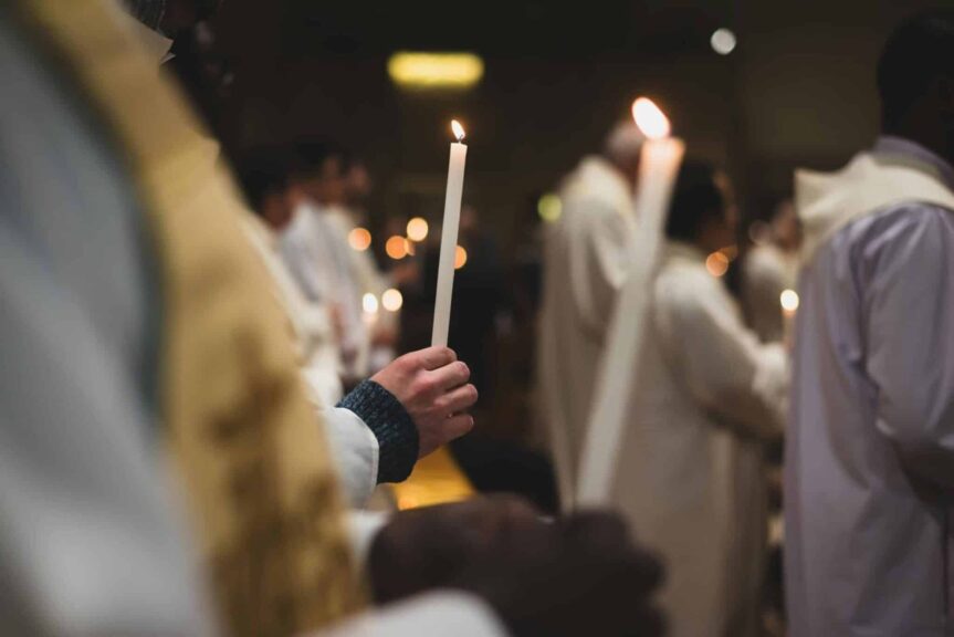 People holding candles in a solemn religious ceremony in a Roman church. Daily devotion