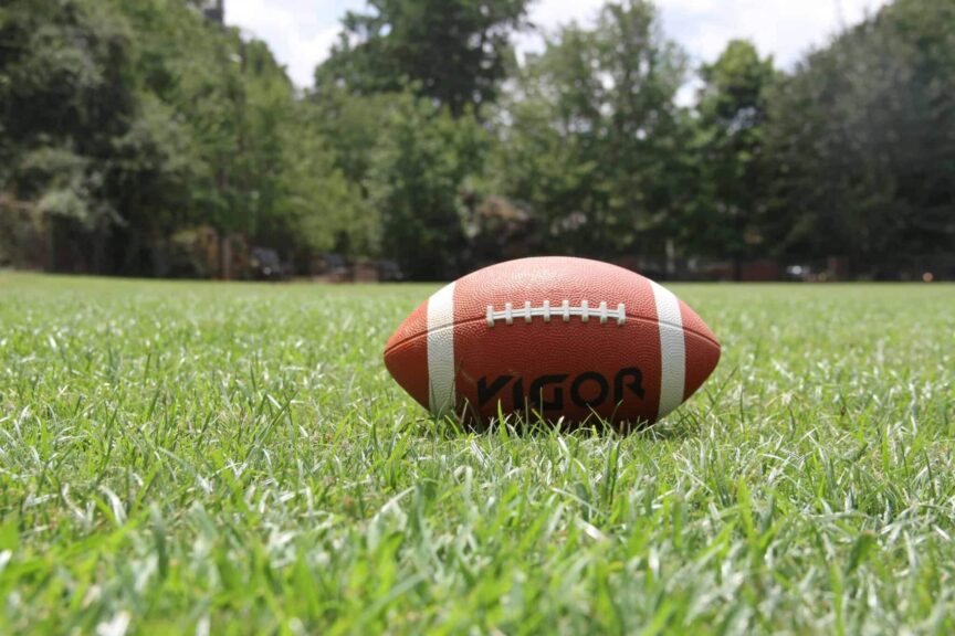 game day food, drinks, A close-up of an American football on a grassy field, highlighting outdoor sports in summer.