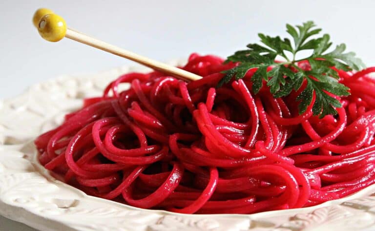 homemade noodles, pasta, red wine, A close-up of vibrant beetroot pasta garnished with fresh parsley on a decorative plate, showcasing colorful and tasty cuisine.