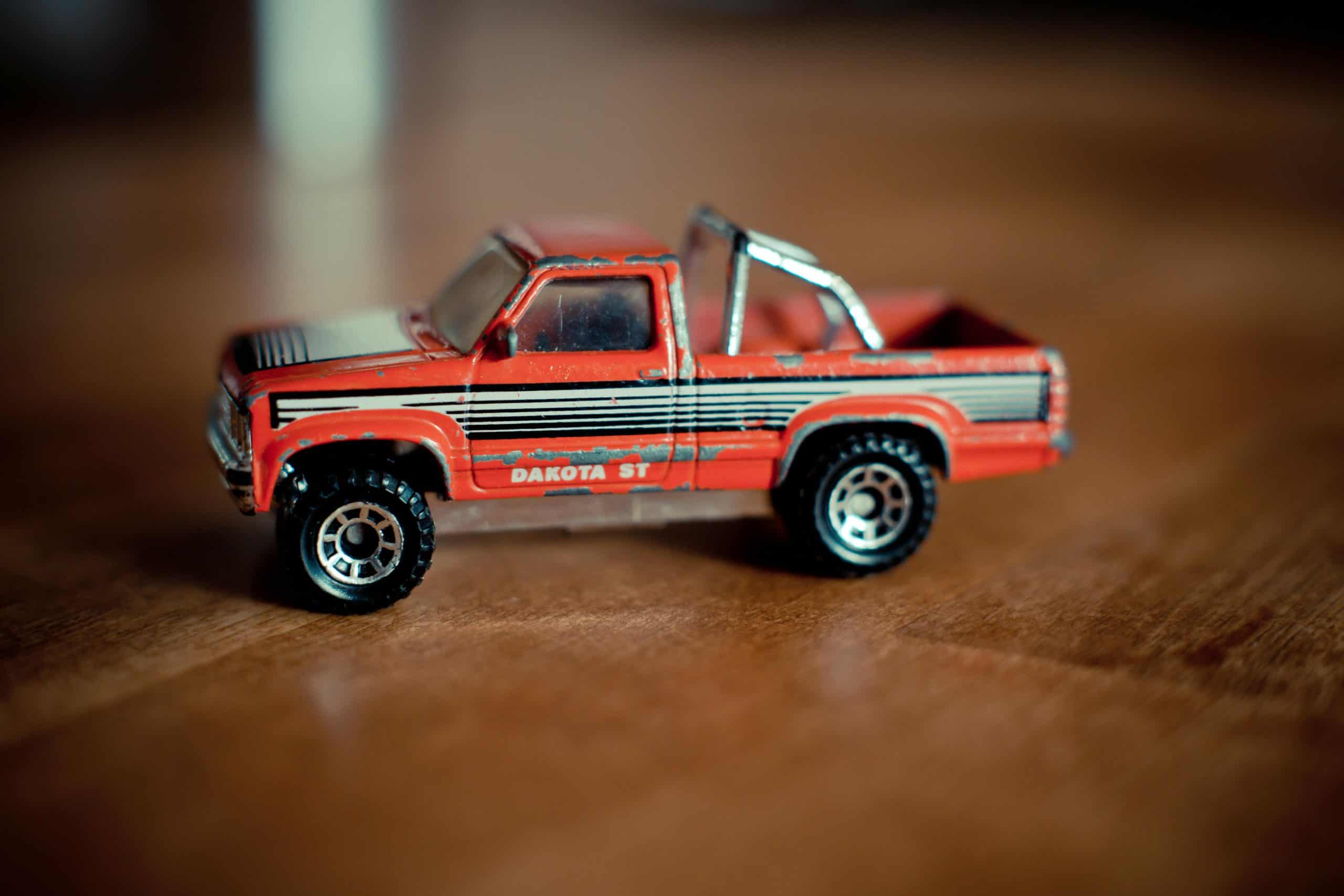 Macro shot of a miniature vintage red pickup toy truck with scratches.