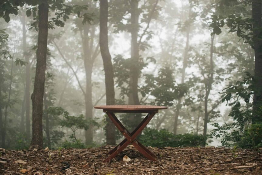 outdoor furniture, winterizing, A wooden table stands alone in a foggy forest, surrounded by dense trees and mist.