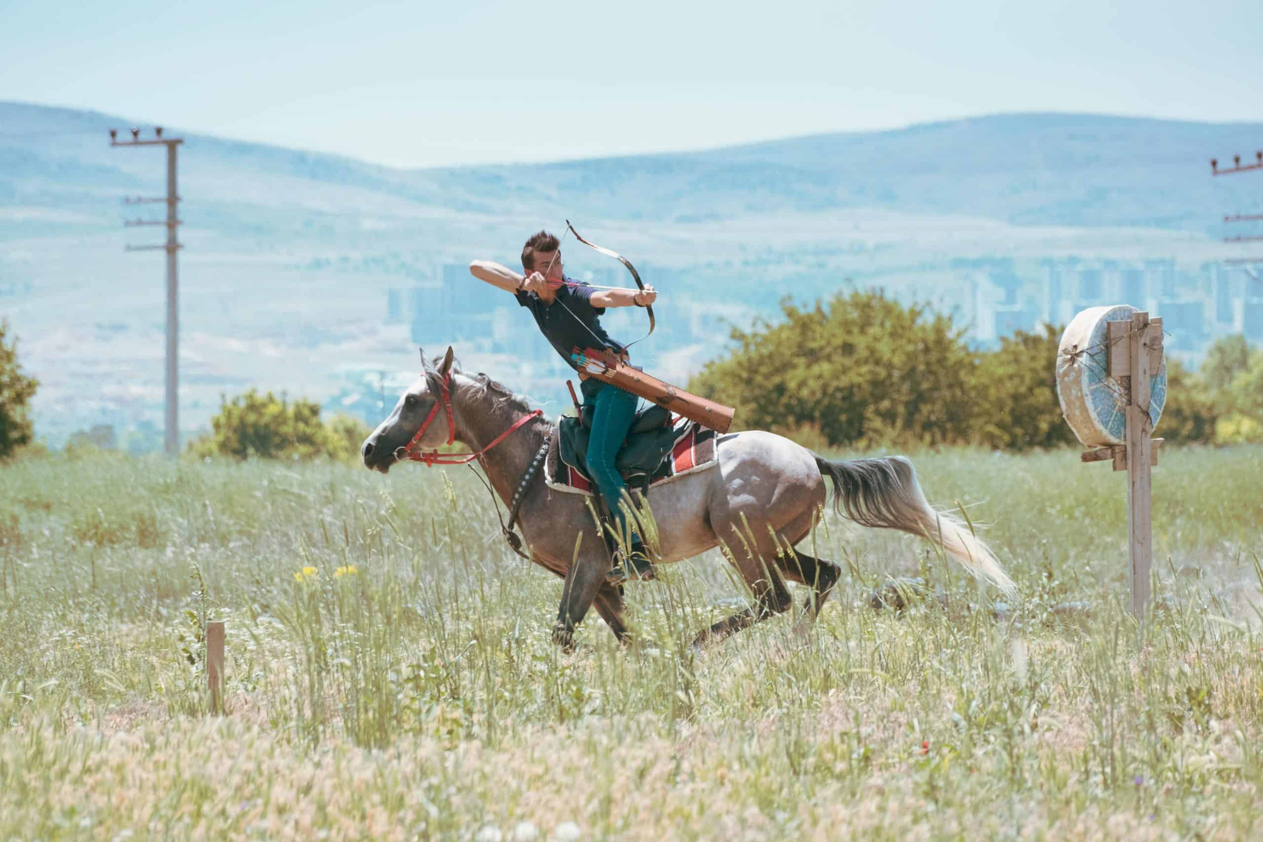 A horseback archer practicing in a lush green field in Konya, Tรผrkiye.