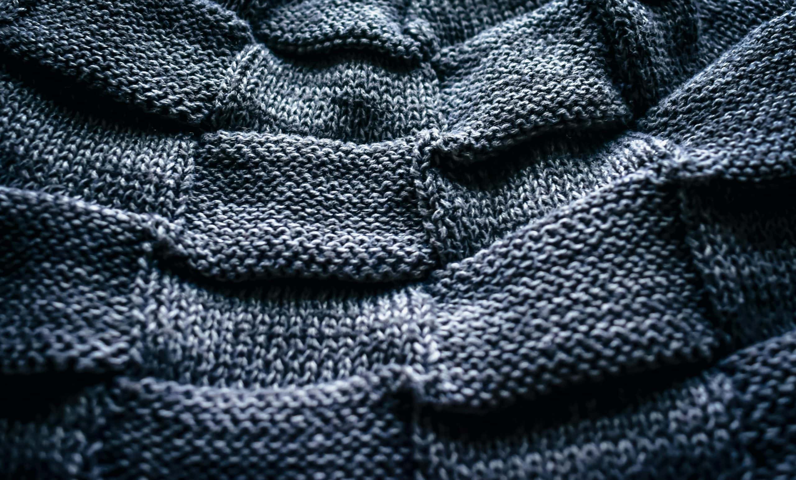 Detailed close-up photo of textured gray knitwear pattern showcasing craftsmanship.