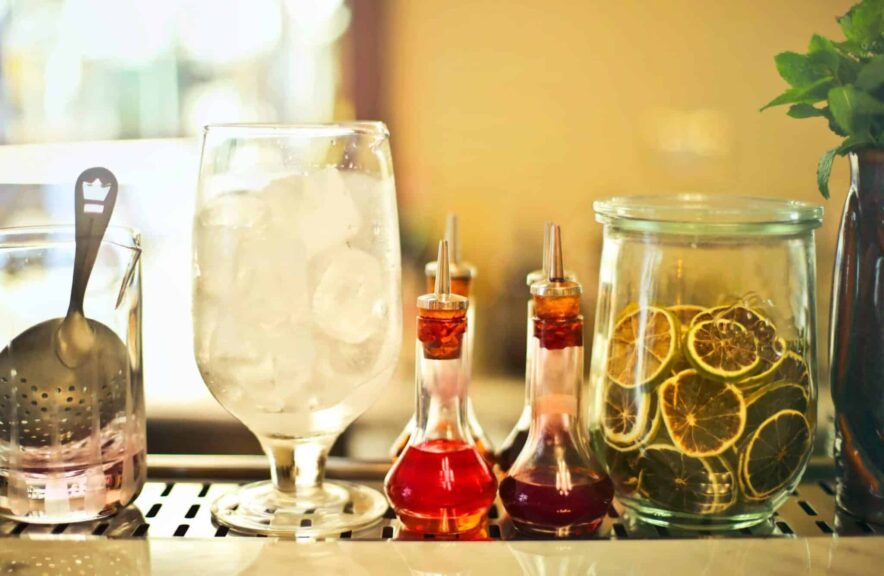 Autumn syrups, Chic cocktail bar setup featuring glassware, citrus slices, and colorful syrups for a refreshing drink experience.
