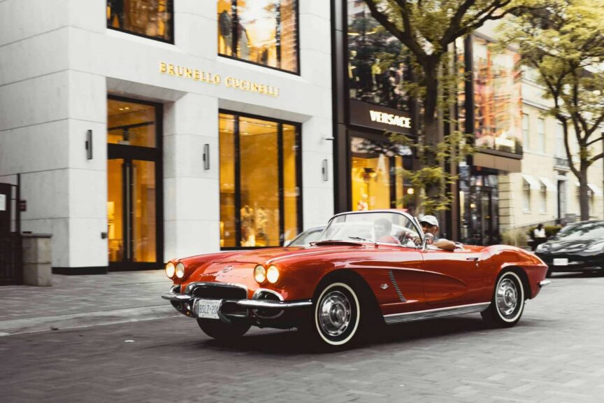 Chevy Corvette Vintage red Chevrolet Corvette convertible driving past luxury shops in Toronto.
